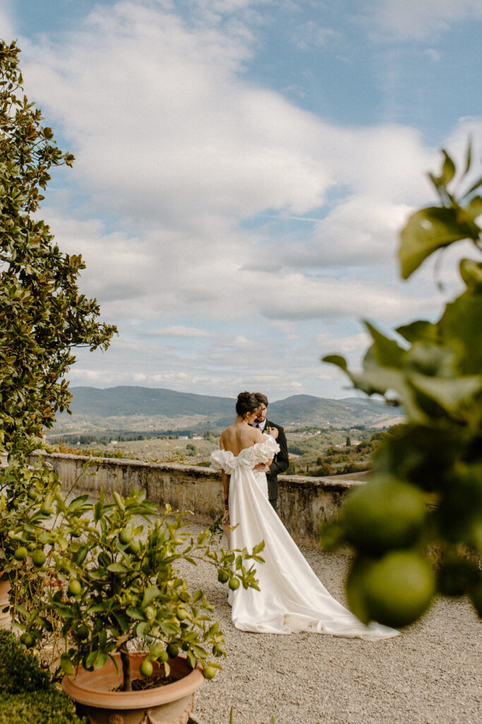 Bride and Groom embrace in romantic garden on Tuscany Wedding Villa with the rolling hills of Tuscany behind them