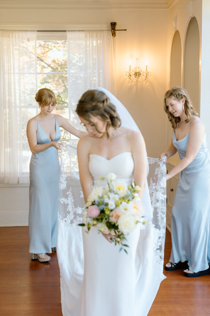 bride's sisters helping her into her veil