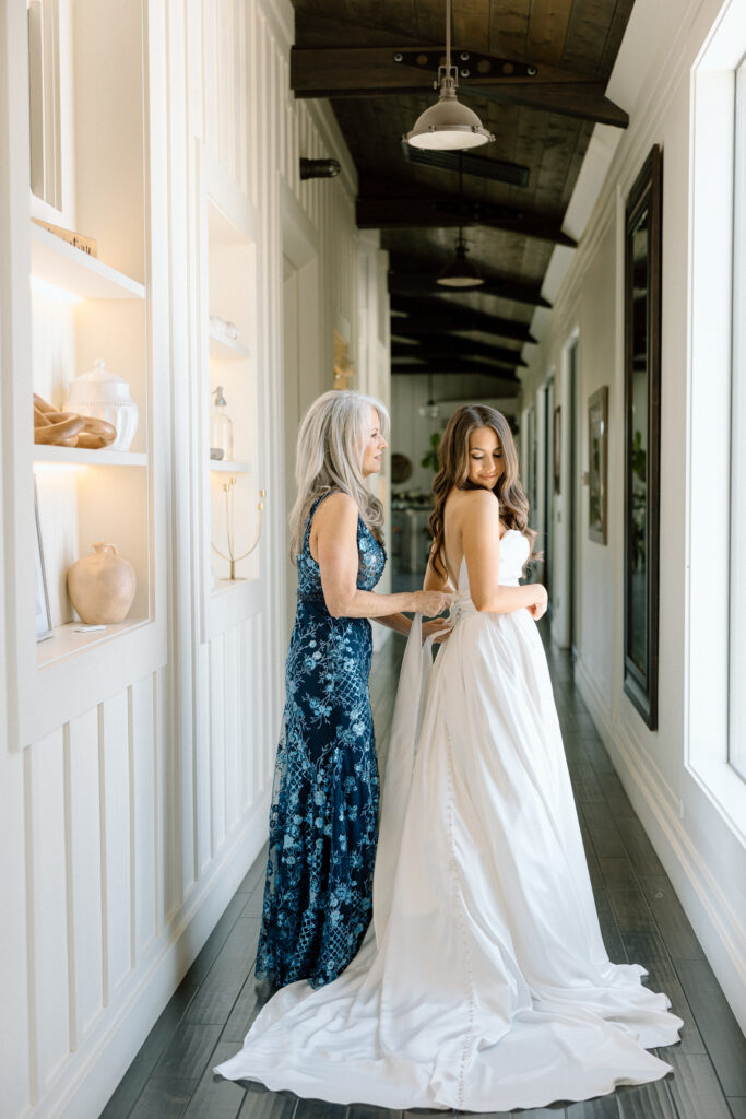 bride's mom helping her into her wedding dress