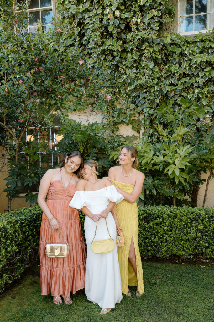 Bride and bridesmaids styled in European-inspired fashion, featuring rust and chartreuse dresses with vintage accessories at an editorial wedding at Château St. Jean.