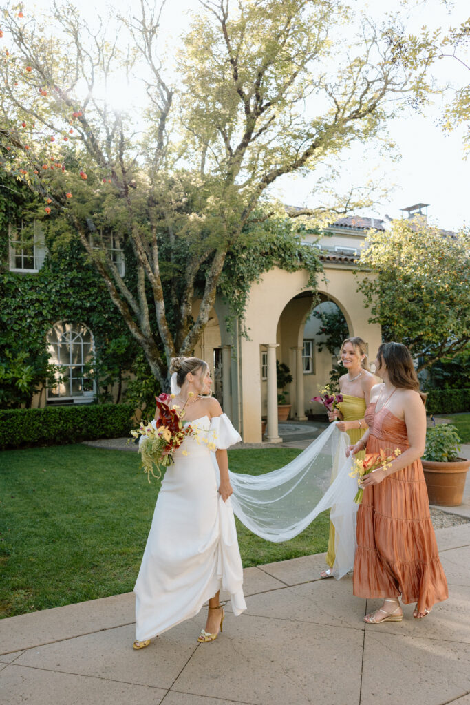 Bride and bridesmaids styled in European-inspired fashion, featuring rust and chartreuse dresses with vintage accessories at an editorial wedding at Château St. Jean.