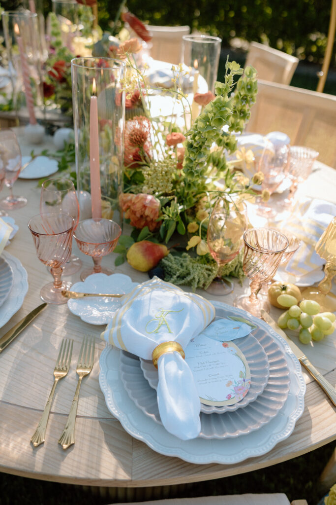 Amalfi Coast–inspired wedding tablescape at Château St. Jean featuring yellow striped linens, fresh citrus, embroidered monogram napkins, and lush floral design