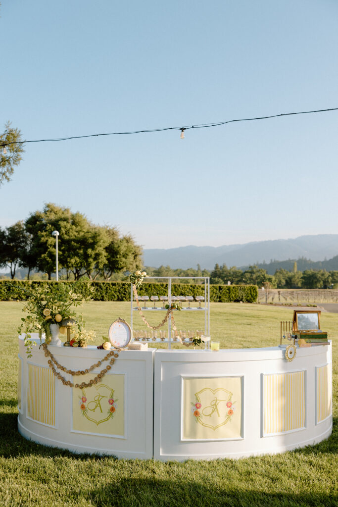 European-inspired wedding cocktail hour at Château St. Jean with citrus details, statement signage, striped linens, and a ‘ring for champagne’ moment in Sonoma Valley.