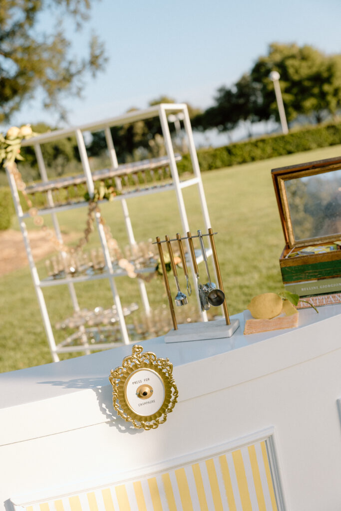 European-inspired wedding cocktail hour at Château St. Jean with citrus details, statement signage, striped linens, and a ‘ring for champagne’ moment in Sonoma Valley.