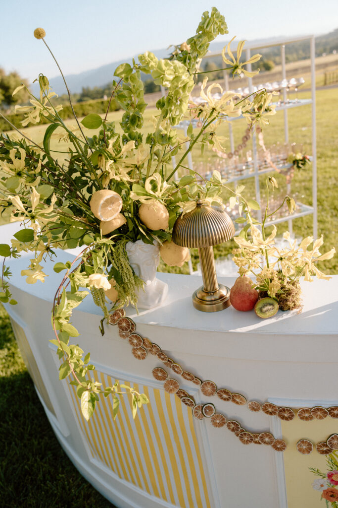 European-inspired wedding cocktail hour at Château St. Jean with citrus details, statement signage, striped linens, and a ‘ring for champagne’ moment in Sonoma Valley.