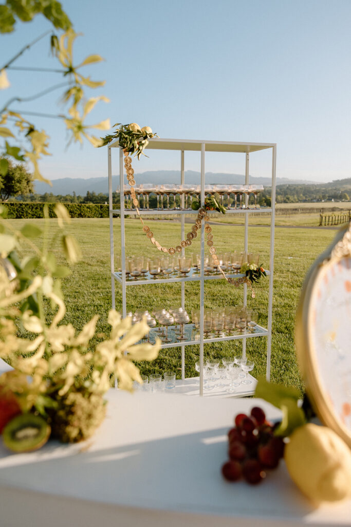 European-inspired wedding cocktail hour at Château St. Jean with citrus details, statement signage, striped linens, and a ‘ring for champagne’ moment in Sonoma Valley.