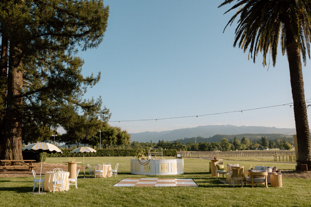 European-inspired wedding cocktail hour at Château St. Jean with citrus details, statement signage, striped linens, and a ‘ring for champagne’ moment in Sonoma Valley.