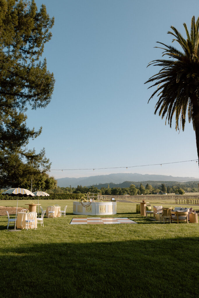 European-inspired wedding cocktail hour at Château St. Jean with citrus details, statement signage, striped linens, and a ‘ring for champagne’ moment in Sonoma Valley.