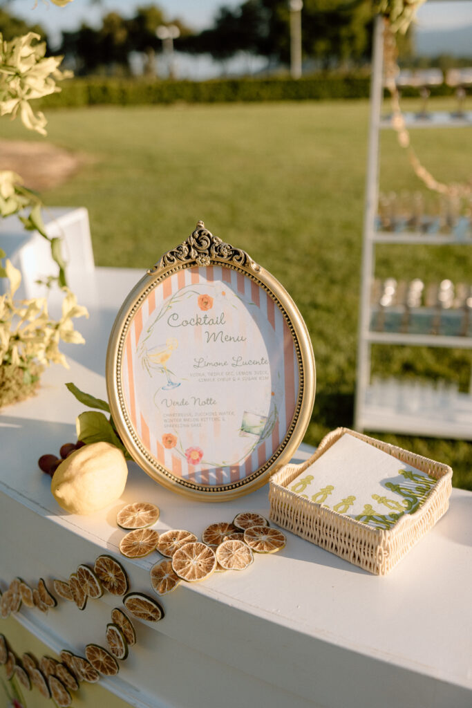 European-inspired wedding cocktail hour at Château St. Jean with citrus details, statement signage, striped linens, and a ‘ring for champagne’ moment in Sonoma Valley.
