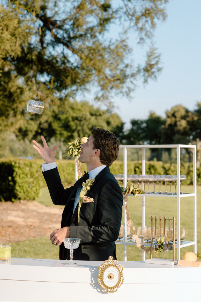 European-inspired wedding cocktail hour at Château St. Jean with citrus details, statement signage, striped linens, and a ‘ring for champagne’ moment in Sonoma Valley.