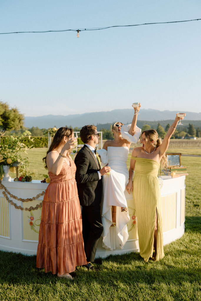 European-inspired wedding cocktail hour at Château St. Jean with citrus details, statement signage, striped linens, and a ‘ring for champagne’ moment in Sonoma Valley.