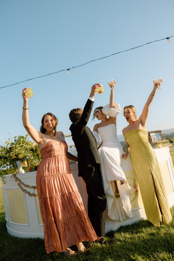 European-inspired wedding cocktail hour at Château St. Jean with citrus details, statement signage, striped linens, and a ‘ring for champagne’ moment in Sonoma Valley.