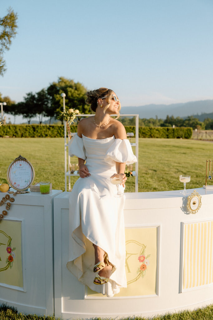 European-inspired wedding cocktail hour at Château St. Jean with citrus details, statement signage, striped linens, and a ‘ring for champagne’ moment in Sonoma Valley.