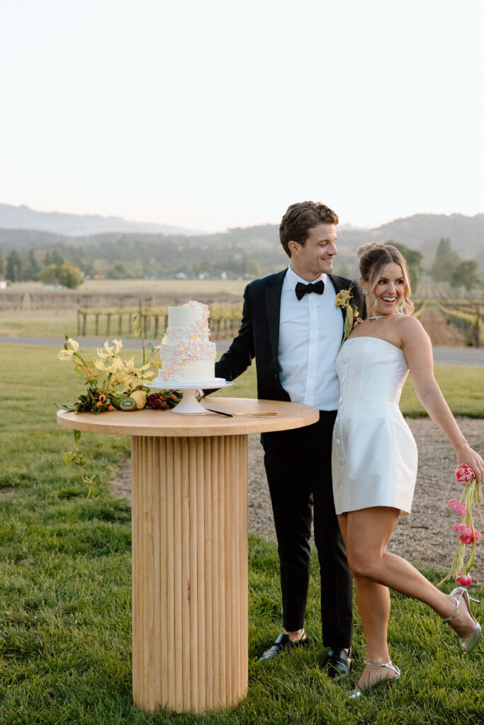 Bride and groom celebrating beside an artistic wedding cake at Château St. Jean during a European-inspired California wedding reception.