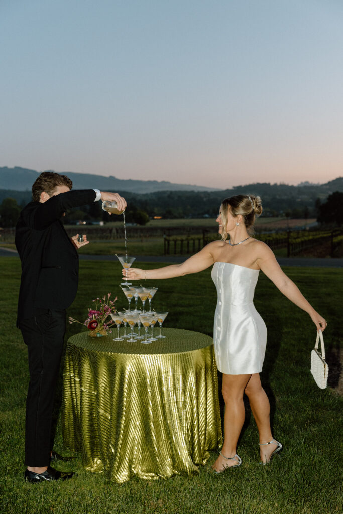 Bride wearing a modern satin mini dress and chartreuse heels during a martini tower celebration at a European-inspired California wedding at Château St. Jean.