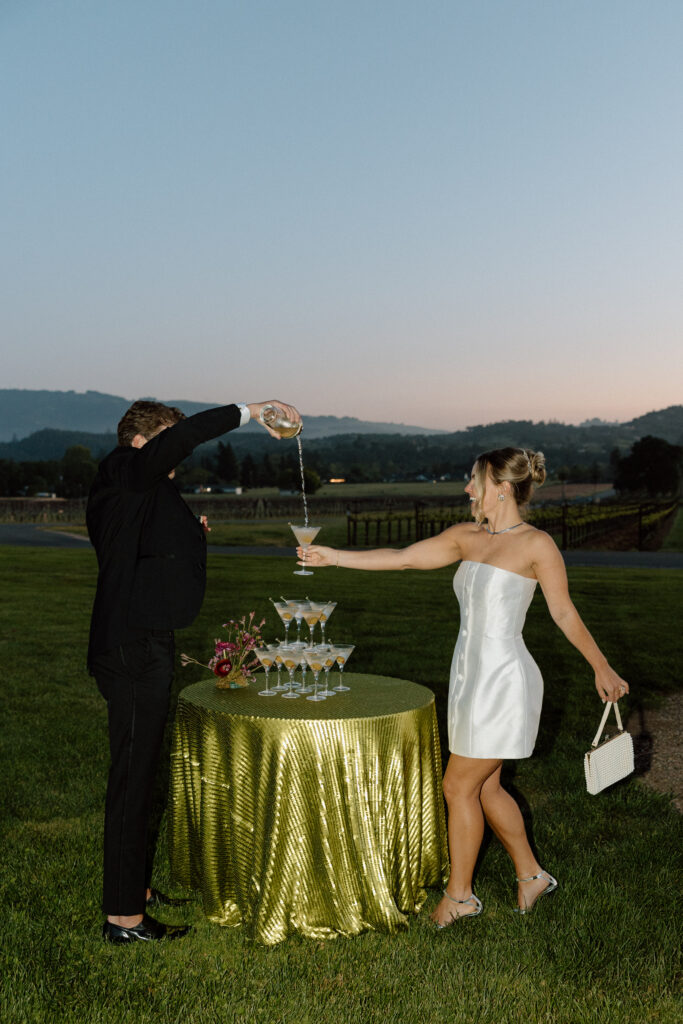 Bride wearing a modern satin mini dress and chartreuse heels during a martini tower celebration at a European-inspired California wedding at Château St. Jean.