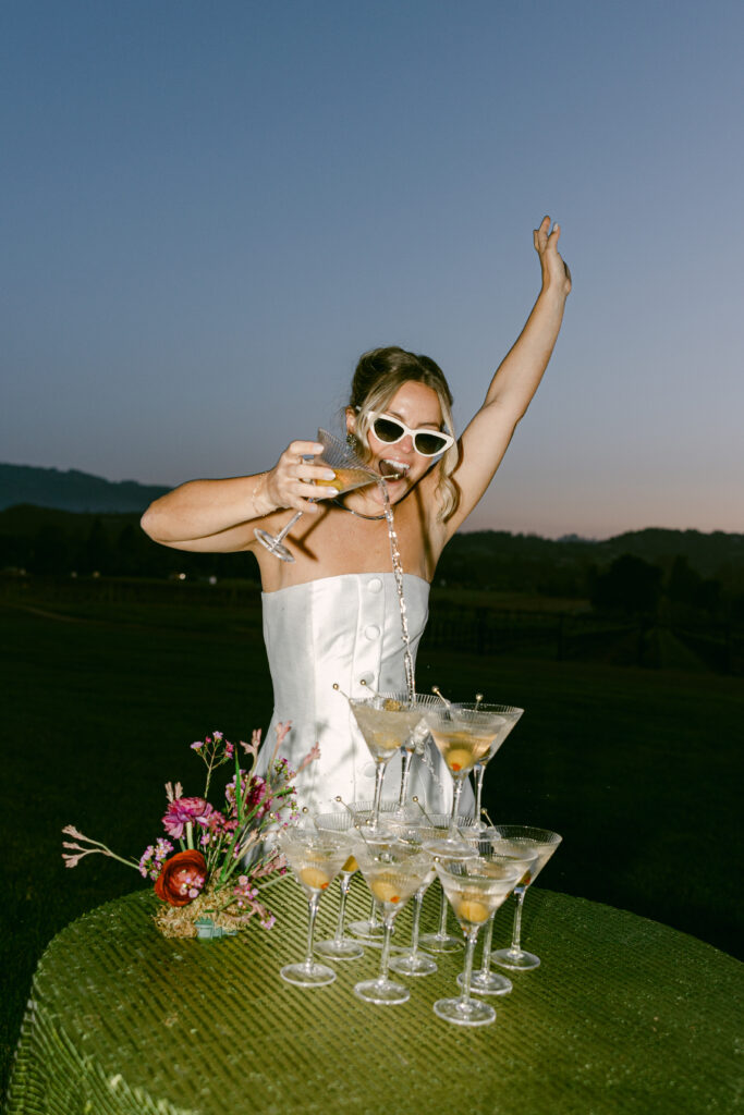 Bride wearing a modern satin mini dress and chartreuse heels during a martini tower celebration at a European-inspired California wedding at Château St. Jean.