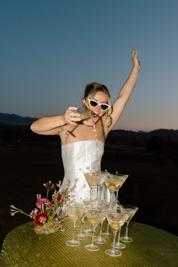 Bride wearing a modern satin mini dress and chartreuse heels during a martini tower celebration at a European-inspired California wedding at Château St. Jean.