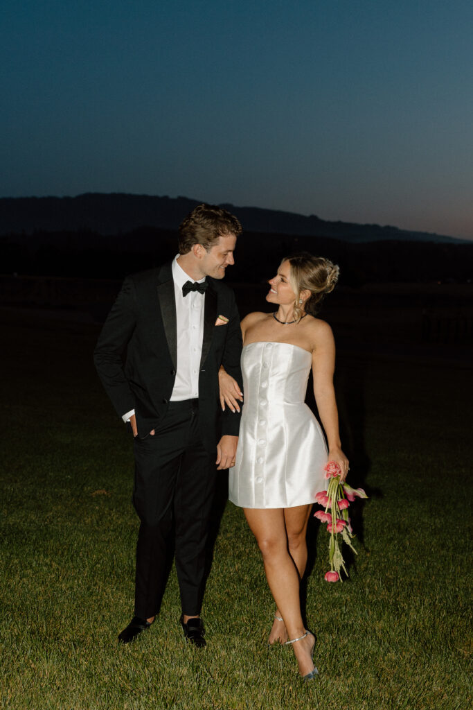 Bride wearing a modern satin mini dress and chartreuse heels during a martini tower celebration at a European-inspired California wedding at Château St. Jean.