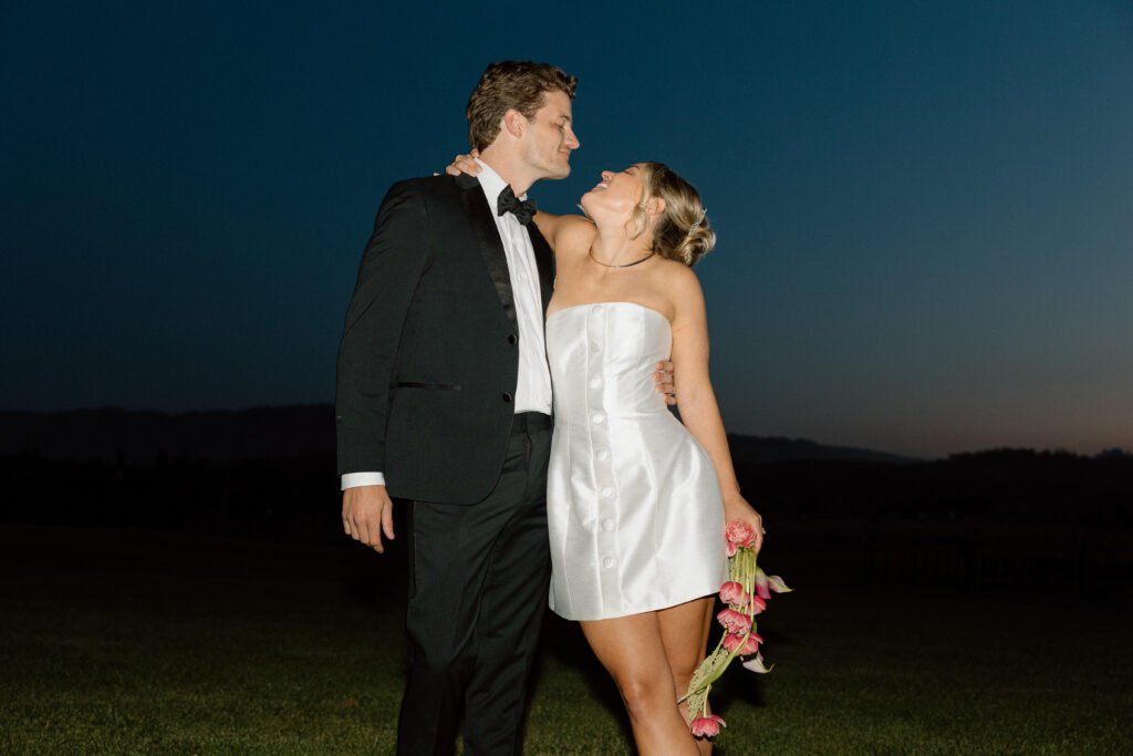 Bride wearing a modern satin mini dress and chartreuse heels during a martini tower celebration at a European-inspired California wedding at Château St. Jean.
