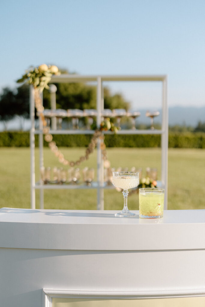 European-inspired wedding cocktail hour at Château St. Jean with citrus details, statement signage, striped linens, and a ‘ring for champagne’ moment in Sonoma Valley.