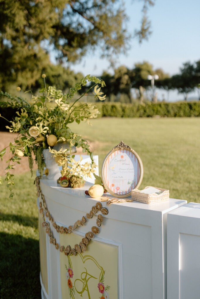 European-inspired wedding cocktail hour at Château St. Jean with citrus details, statement signage, striped linens, and a ‘ring for champagne’ moment in Sonoma Valley.