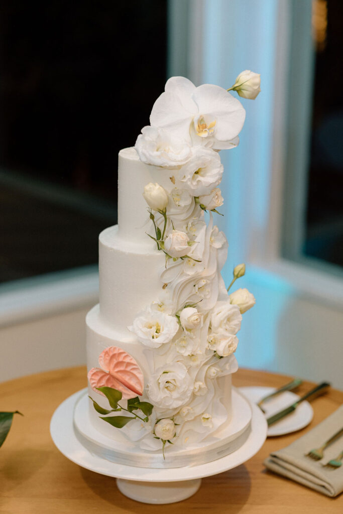Bride and groom cutting their wedding cake inside the reception space following a sailboat ceremony exit