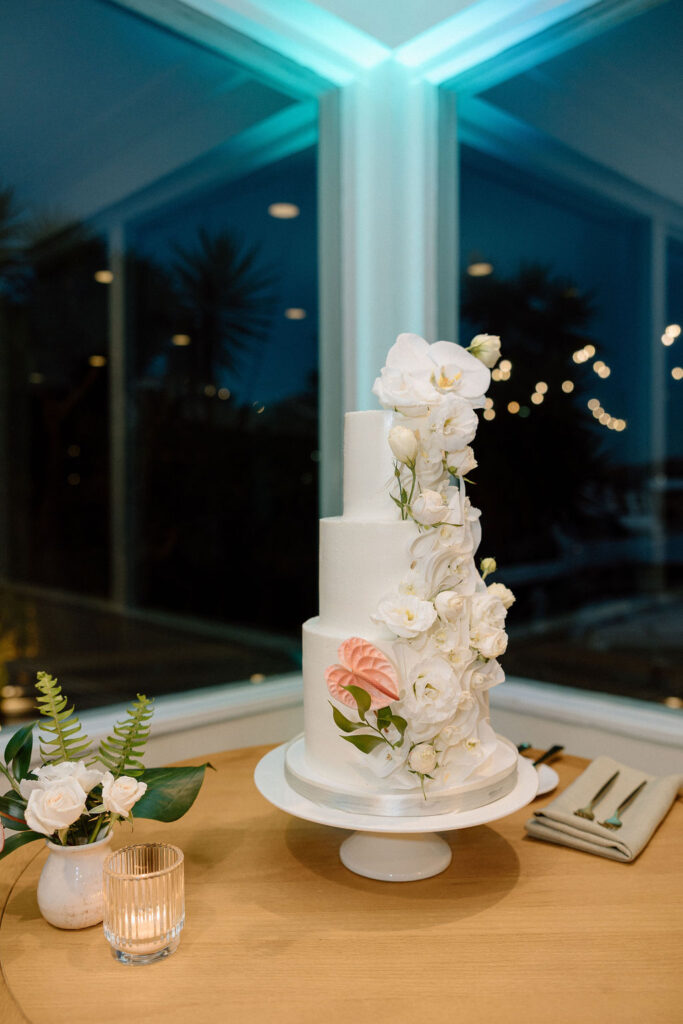 Bride and groom cutting their wedding cake inside the reception space following a sailboat ceremony exit
