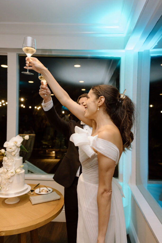 Bride and groom cutting their wedding cake inside the reception space following a sailboat ceremony exit