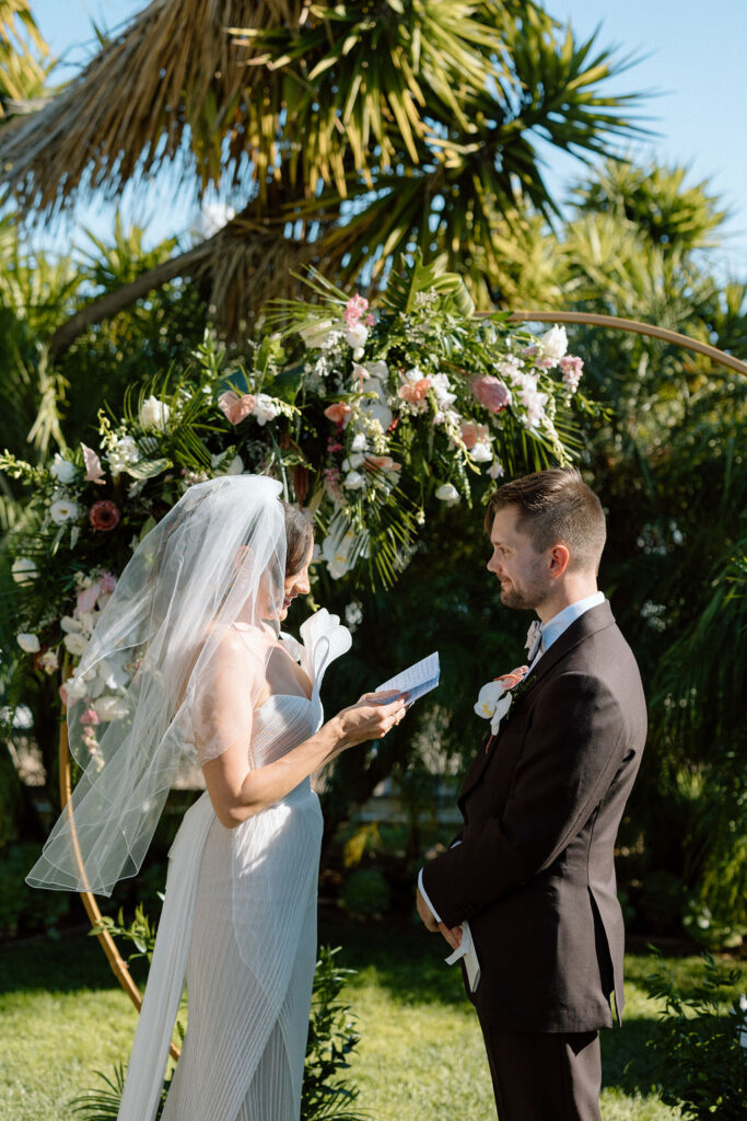 Bride and groom exchanging vows during an outdoor ceremony at Glen Cove Marina, surrounded by palm trees and sailboats in Northern California