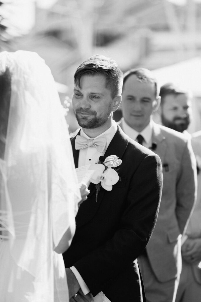 Bride and groom exchanging vows during an outdoor ceremony at Glen Cove Marina, surrounded by palm trees and sailboats in Northern California