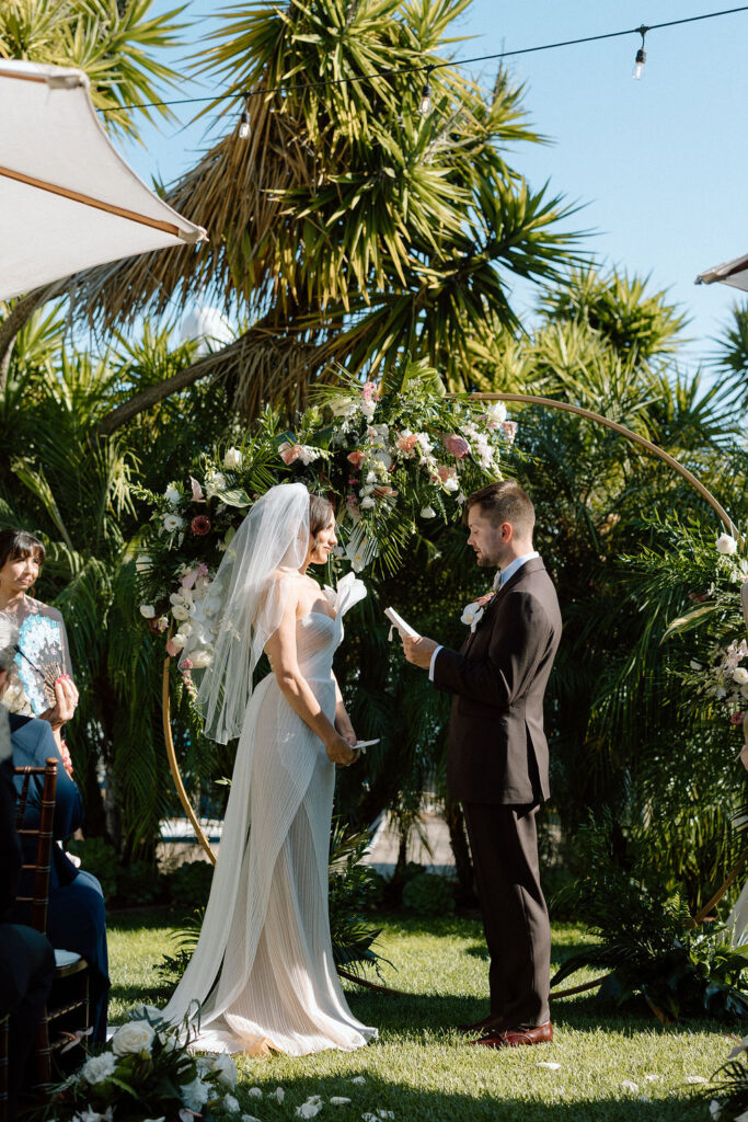 Bride and groom exchanging vows during an outdoor ceremony at Glen Cove Marina, surrounded by palm trees and sailboats in Northern California