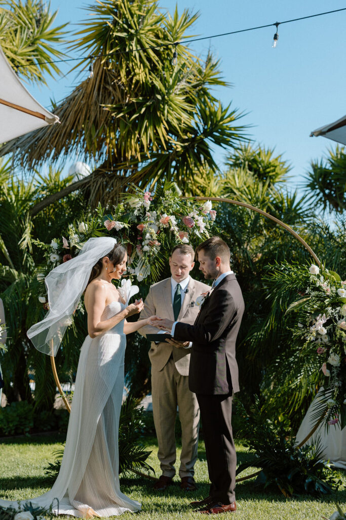 Bride and groom exchanging vows during an outdoor ceremony at Glen Cove Marina, surrounded by palm trees and sailboats in Northern California