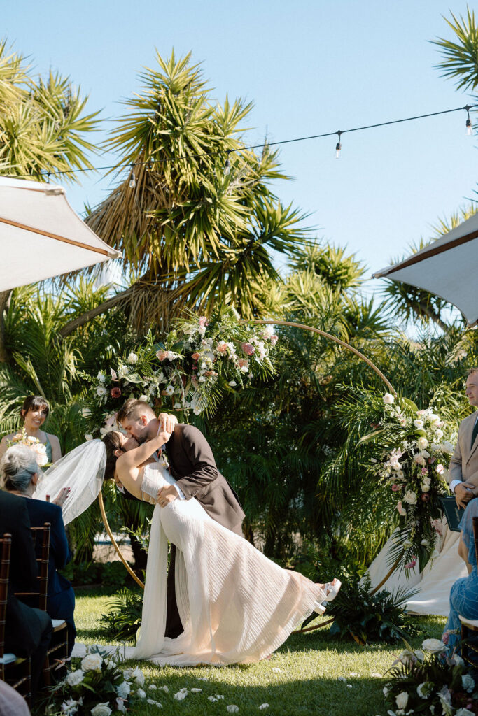 Bride and groom exchanging vows during an outdoor ceremony at Glen Cove Marina, surrounded by palm trees and sailboats in Northern California