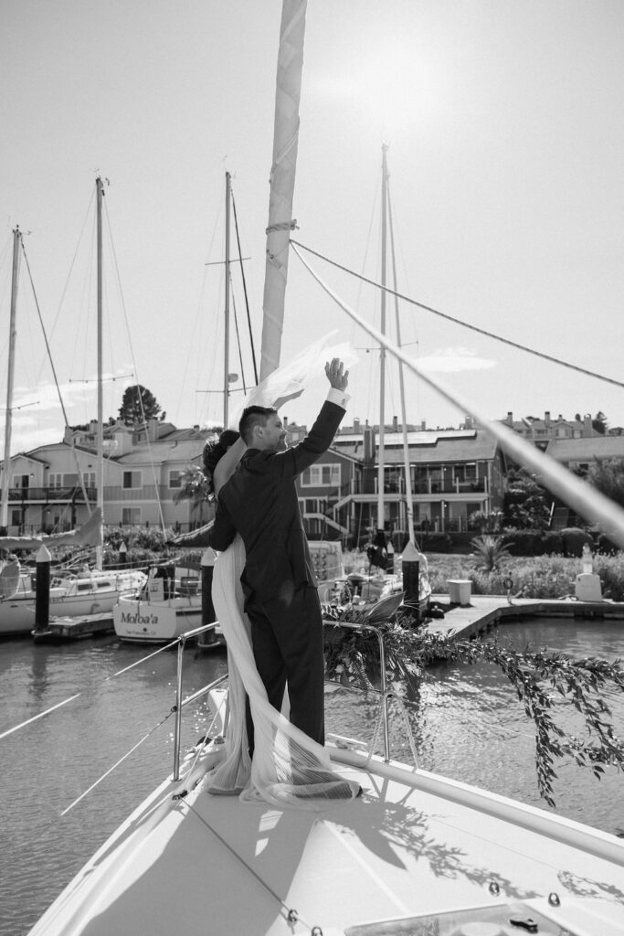 Newly married couple walking hand-in-hand from their ceremony to a sailboat dock at a Northern California marina wedding