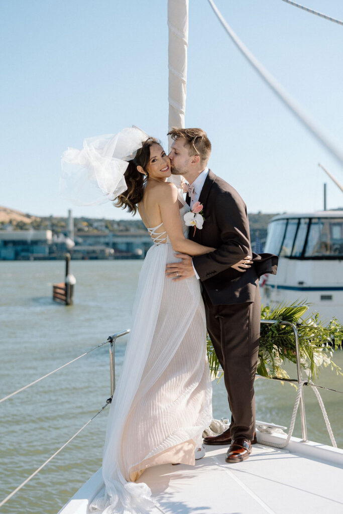 Bride wearing a flowing wedding gown in ocean breeze during a Northern California sailboat wedding