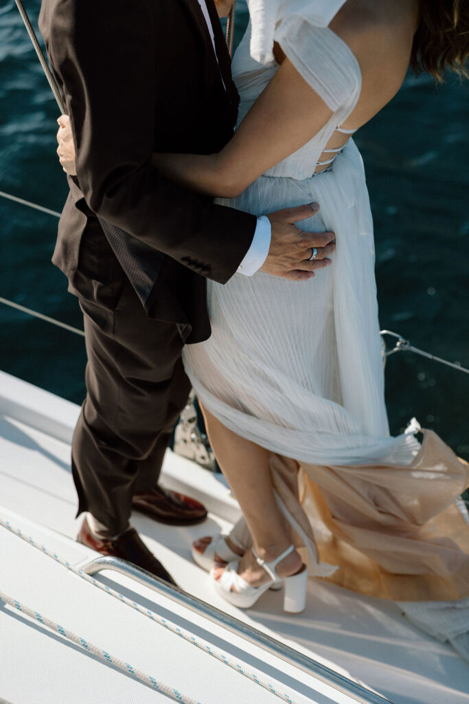 Bride wearing a flowing wedding gown in ocean breeze during a Northern California sailboat wedding