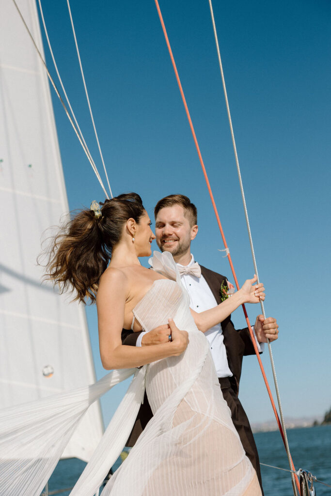 Bride wearing a flowing wedding gown in ocean breeze during a Northern California sailboat wedding