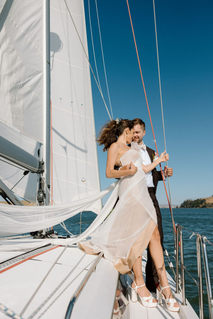 Bride wearing a flowing wedding gown in ocean breeze during a Northern California sailboat wedding