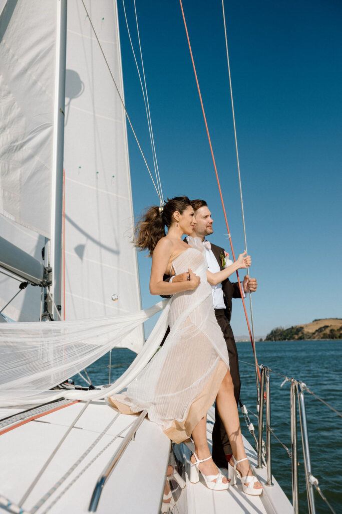 Bride wearing a flowing wedding gown in ocean breeze during a Northern California sailboat wedding