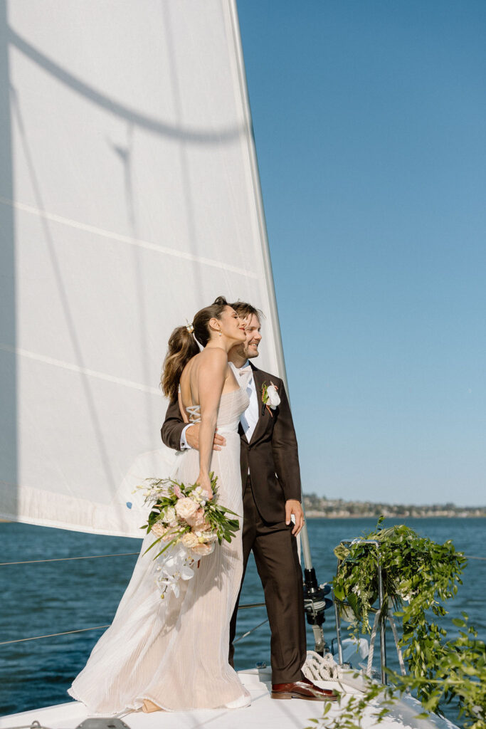 Bride wearing a flowing wedding gown in ocean breeze during a Northern California sailboat wedding