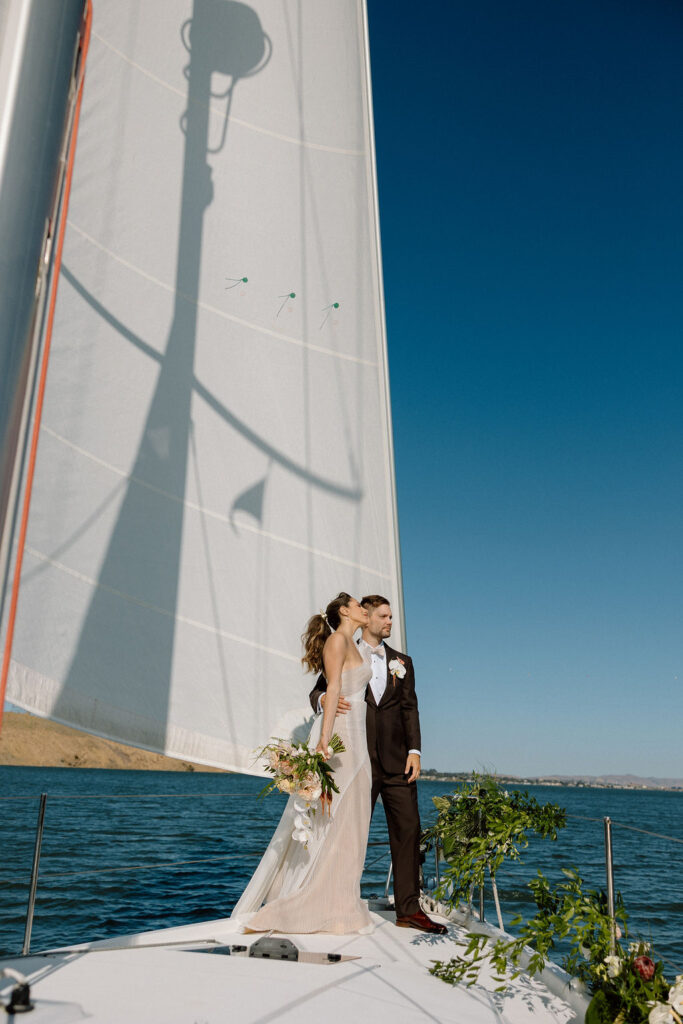 Bride wearing a flowing wedding gown in ocean breeze during a Northern California sailboat wedding