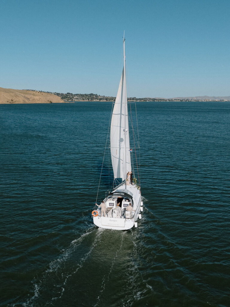 Bride wearing a flowing wedding gown in ocean breeze during a Northern California sailboat wedding