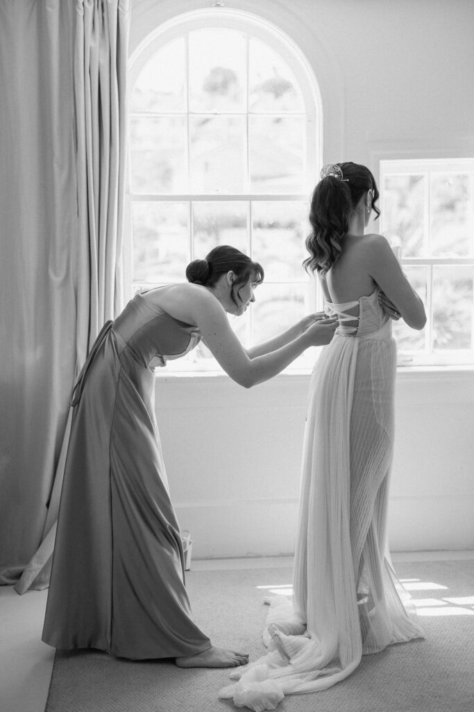 Bride getting ready with natural light pouring into the room before her Northern California sailboat wedding