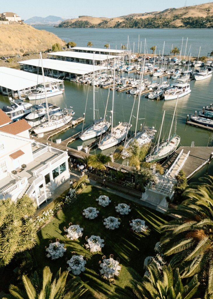 Golden hour dinner reception beneath palm trees and string lights at a Glen Cove Marina wedding