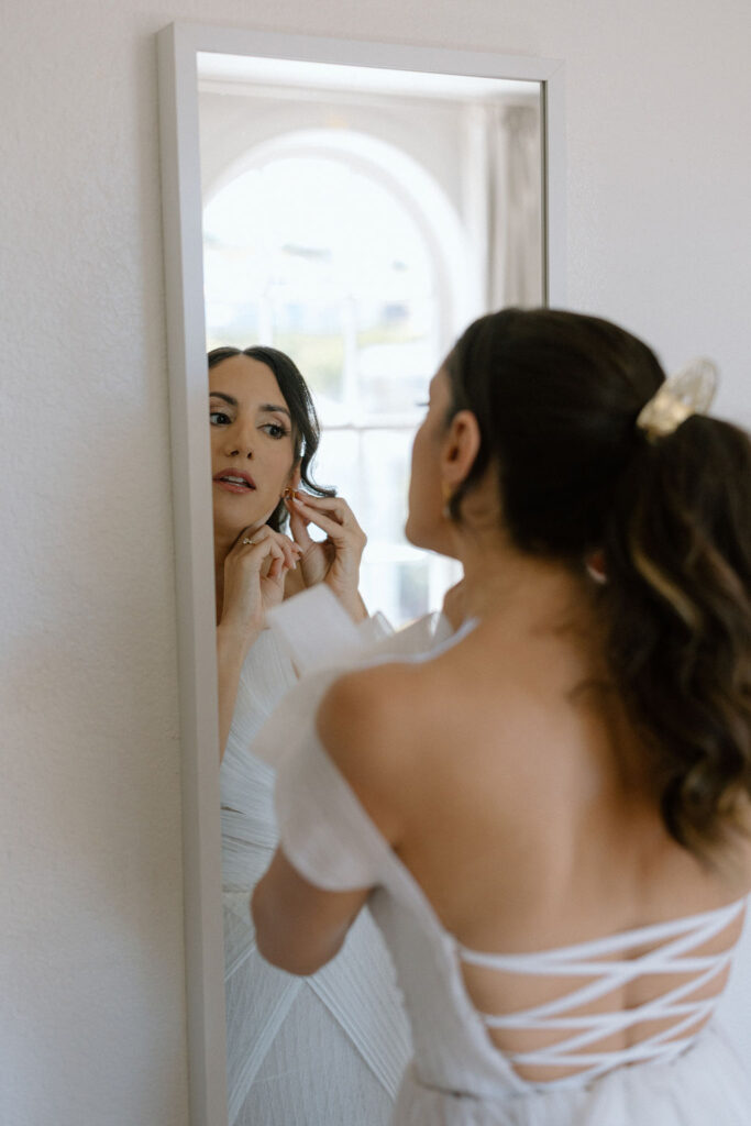 Bride getting ready with natural light pouring into the room before her Northern California sailboat wedding