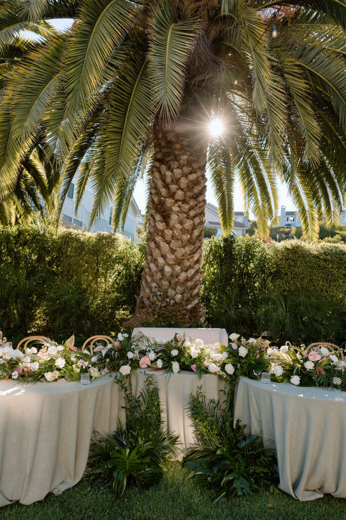 Golden hour dinner reception beneath palm trees and string lights at a Glen Cove Marina wedding
