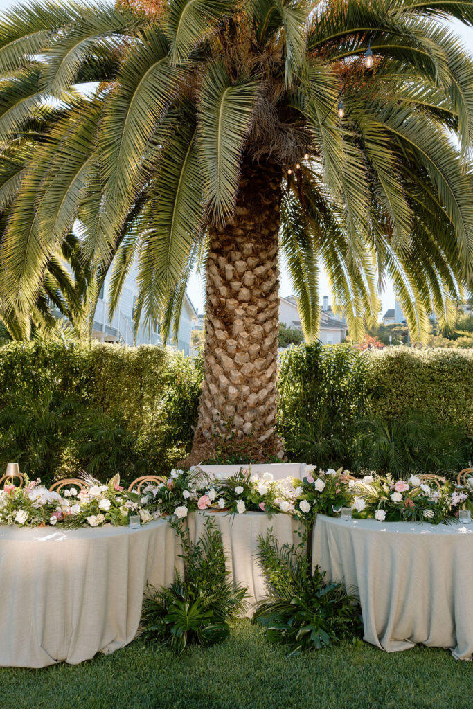 Outdoor wedding reception at Glen Cove Marina with serpentine head table, lush florals, and golden sunset light