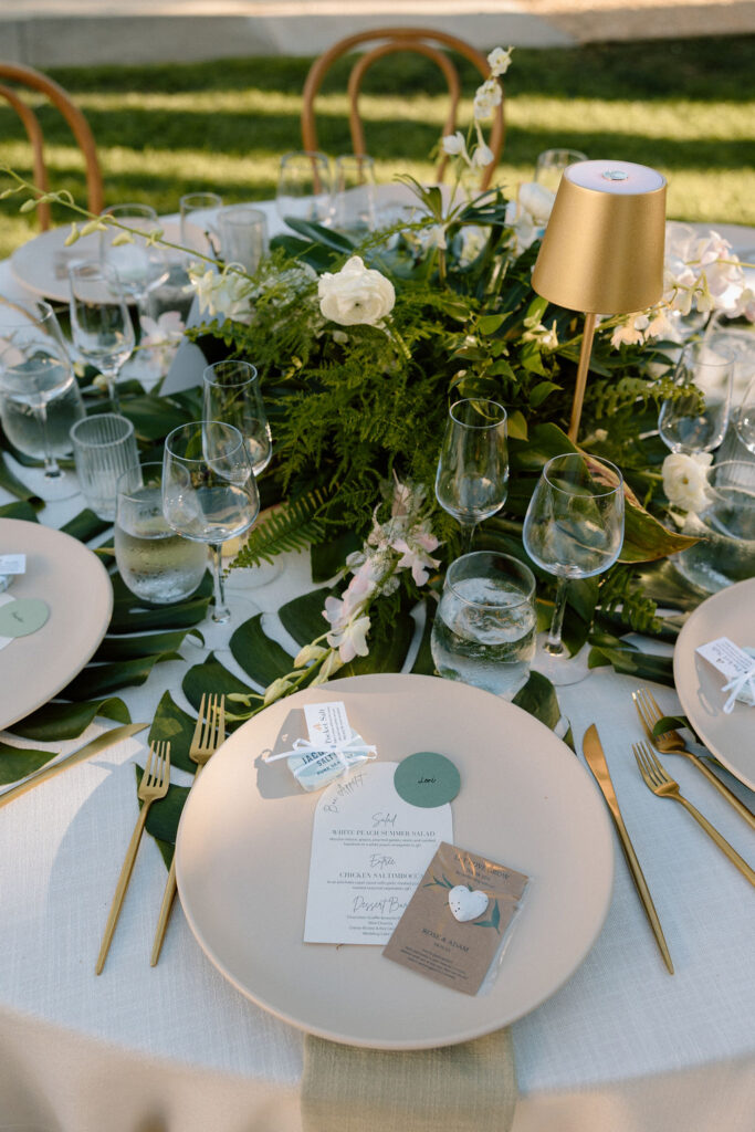 Outdoor wedding reception at Glen Cove Marina with serpentine head table, lush florals, and golden sunset light