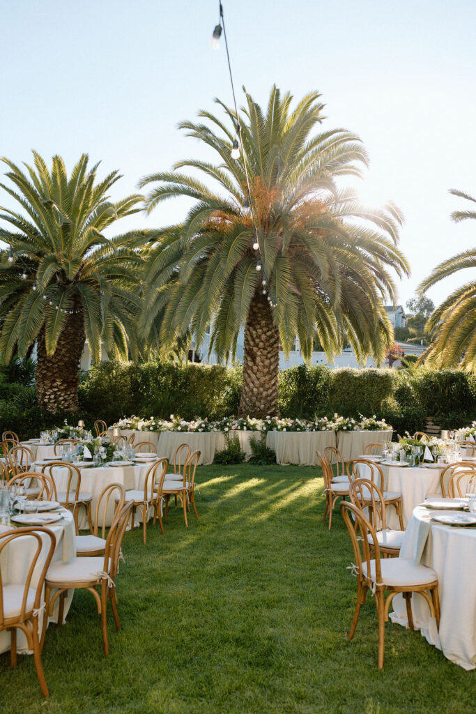 Outdoor wedding reception at Glen Cove Marina with serpentine head table, lush florals, and golden sunset light